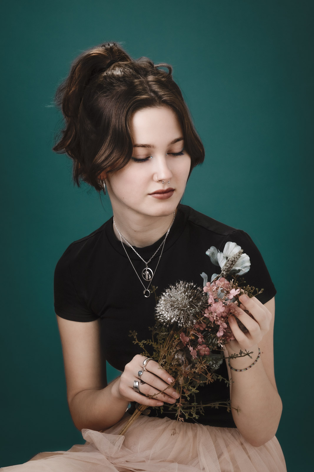 Ung kvinde kigger på en blomst mens hun fotograferes