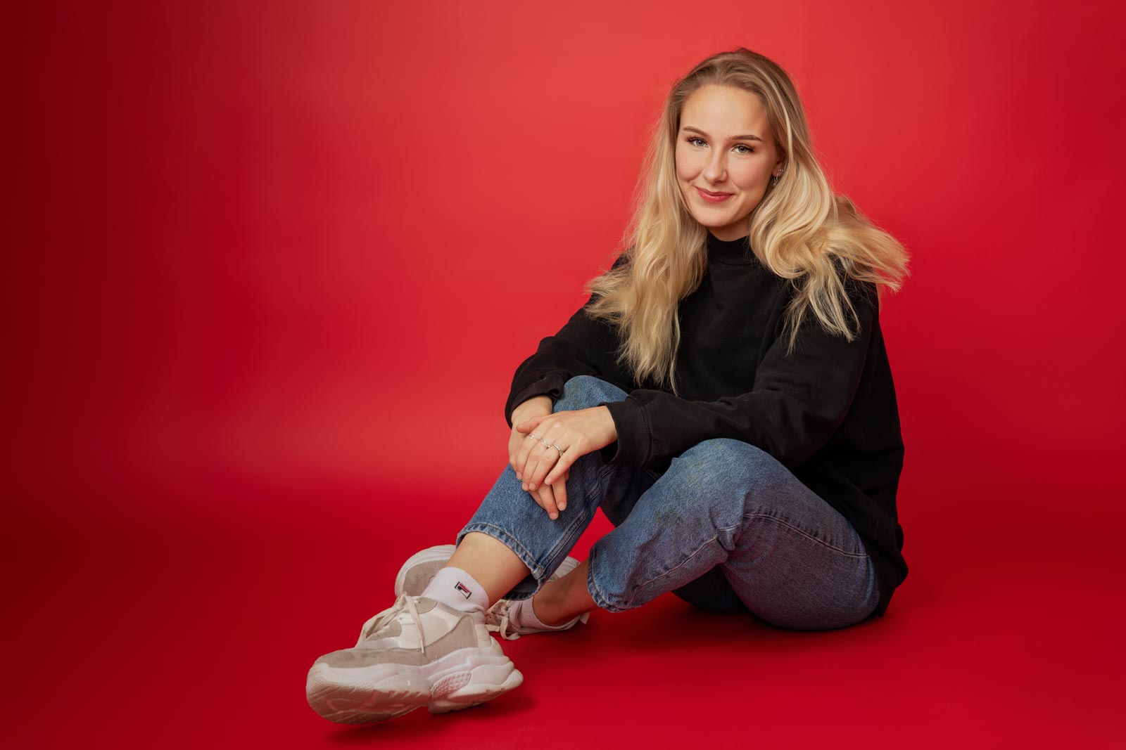 ung og smilende teenager på gulvet i fotostudiet